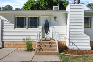 Entrance to property with a chimney and a shingled roof