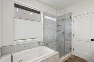 Bathroom featuring a garden tub and a marble finish shower