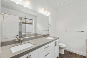 Full bath with a stall shower, double vanity, and dark tile patterned floors