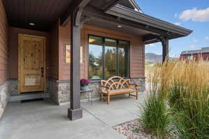 Entrance to property with stone siding, a mountain view, and a patio area