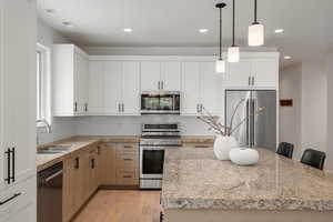 Kitchen featuring pendant lighting, light stone countertops, appliances with stainless steel finishes, backsplash, and recessed lighting