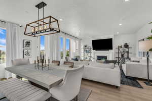 Dining area featuring a fireplace, light wood-style flooring, recessed lighting, and a textured ceiling
