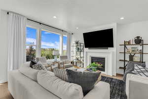 Living room with light wood-style floors, a glass covered fireplace, recessed lighting, and a textured ceiling