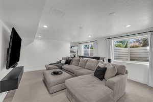 Living room with light colored carpet, recessed lighting, and a textured ceiling
