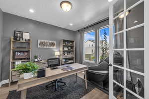 Office area with light wood-style floors, recessed lighting, and a textured ceiling