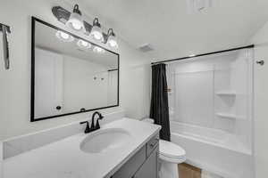 Bathroom with shower / bathtub combination with curtain, vanity, a textured ceiling, and wood finished floors