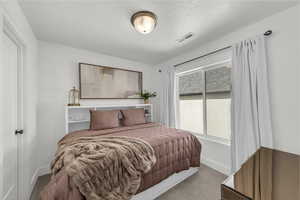 Carpeted bedroom featuring baseboards and a textured ceiling