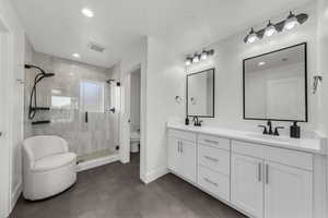 Full bath featuring a stall shower, double vanity, and recessed lighting