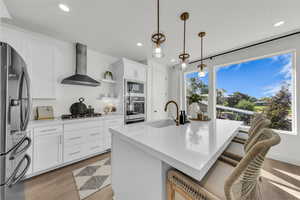 Kitchen featuring white cabinets, light wood-style flooring, a kitchen breakfast bar, open shelves, and recessed lighting