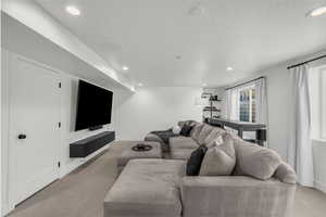 Living area with light colored carpet, recessed lighting, and a textured ceiling