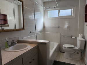 Bathroom with tile walls, a bath, and vanity