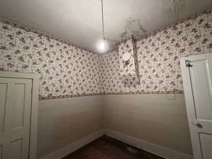 Spare room featuring dark wood-style floors and wallpapered walls