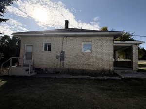 Rear view of property featuring a yard, brick siding, a patio, and a chimney