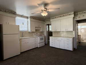 Kitchen with light countertops, white appliances, white cabinetry, and a ceiling fan
