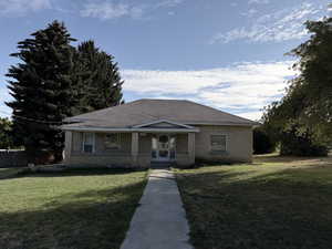 Bungalow-style home with a front yard and brick siding