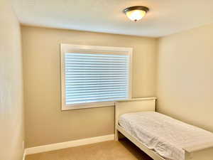 Carpeted bedroom featuring baseboards and a textured ceiling
