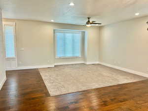 Empty room with healthy amount of natural light, a textured ceiling, dark wood-style floors, recessed lighting, and ceiling fan