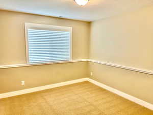 Carpeted empty room featuring baseboards and a textured ceiling