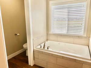 Bathroom featuring dark wood-type flooring and a garden tub