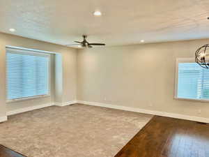 Unfurnished room with recessed lighting, dark wood finished floors, a textured ceiling, a chandelier, and dark colored carpet