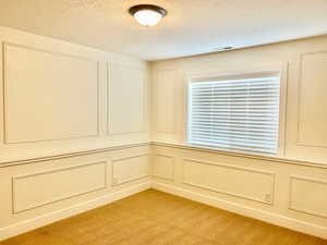 Spare room with a decorative wall, light colored carpet, and a textured ceiling