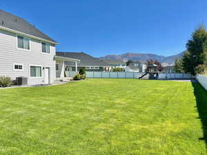 Fenced backyard featuring a playground, a mountain view, and a patio