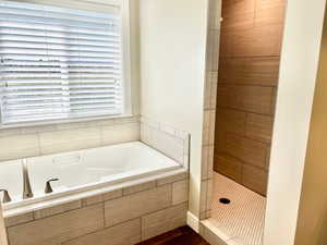 Full bathroom with a bath, a stall shower, plenty of natural light, and dark wood-style floors