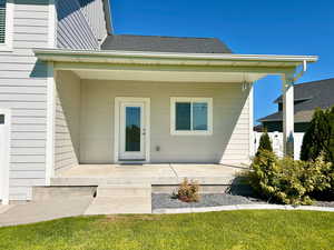 Entrance to property featuring covered porch, roof with shingles, and a yard