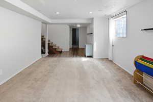 Basement featuring stairs, light carpet, and recessed lighting