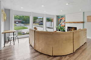 Living area with a textured ceiling, light wood-style flooring, recessed lighting, and a lit fireplace