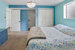Carpeted bedroom featuring a chandelier and a closet