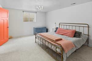 Bedroom with light carpet, a textured ceiling, and a chandelier