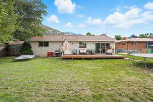 Back of house featuring brick siding, a deck with mountain view, a patio area, and a chimney