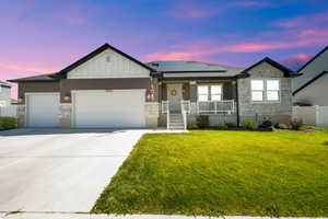 Single story home with stone siding, a porch, a garage, driveway, and board and batten siding