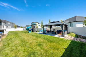 Fenced backyard with a playground, outdoor lounge area, a gazebo, a residential view, and a patio