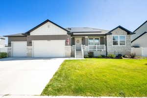 View of front facade with stone siding, board and batten siding, a porch, and a garage