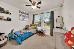 Bedroom with light colored carpet and a ceiling fan