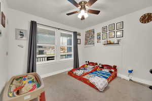 Carpeted bedroom featuring ceiling fan and baseboards