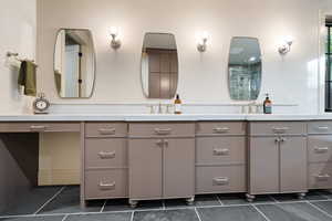 Bathroom with double vanity, a shower with door, and dark tile patterned floors