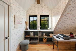 Office area with wallpapered walls and light wood-style flooring