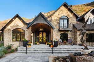 View of exterior entry featuring french doors, stone siding, and a patio