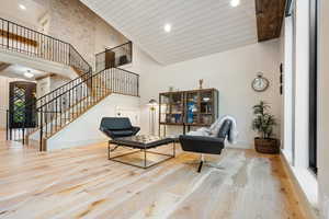Living area with wood finished floors, recessed lighting, stairway, high vaulted ceiling, and wooden ceiling