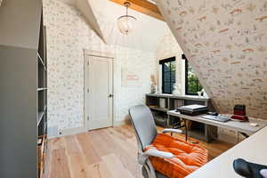 Home office with wallpapered walls, light wood-style flooring, and a chandelier