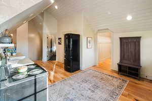 Kitchen featuring freestanding refrigerator, light wood-style floors, recessed lighting, and high vaulted ceiling