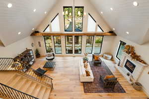 Living room with recessed lighting, a chandelier, a glass covered fireplace, light wood-style floors, and high vaulted ceiling