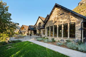 Rear view of property featuring stone siding, a patio area, and a standing seam roof