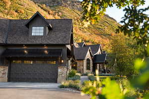 View of front facade with board and batten siding, stone siding, a standing seam roof, concrete driveway, and a metal roof
