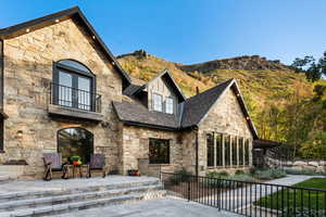 View of front of house with stone siding, a patio, a balcony, and a mountain view