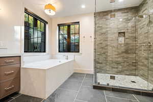 Full bath with a stall shower, a bath, vanity, dark tile patterned floors, and recessed lighting
