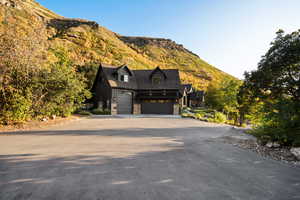 View of front of property featuring stone siding, driveway, a mountain view, and an attached garage
